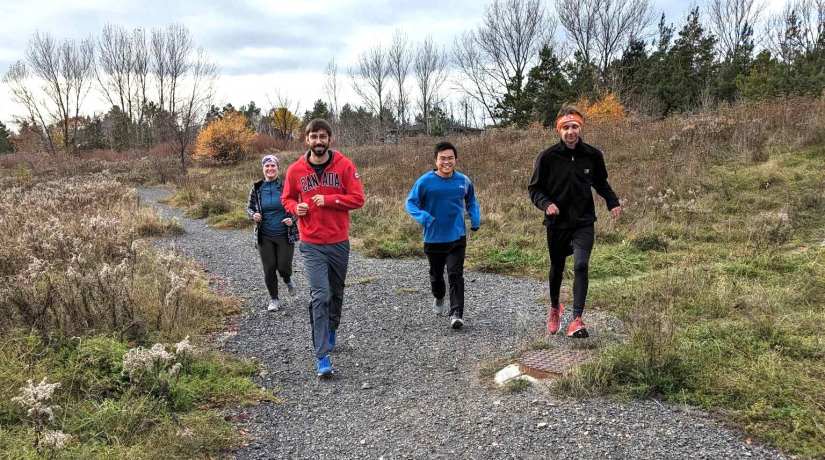 Four students run on a gravel path