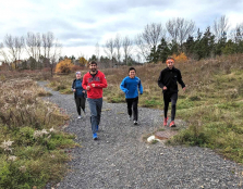 Four students run on a gravel trail